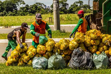 Belediye çalışanları halka açık bir parkta çöpleri topluyor..