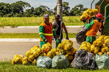 Belediye çalışanları halka açık bir parkta çöpleri topluyor..