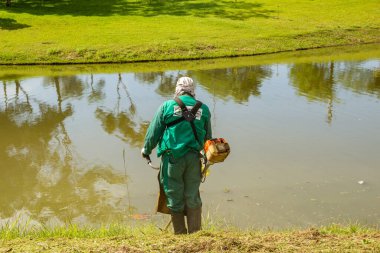 Belediye binasında halka açık bir parkta bahçe bakımı yapan bir profesyonel. Çimleri buduyorum..