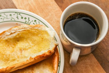 Tabakta iki çörek ve tahta bir yüzeyde bir fincan kahve..