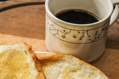 Tabakta iki çörek ve tahta bir yüzeyde bir fincan kahve..