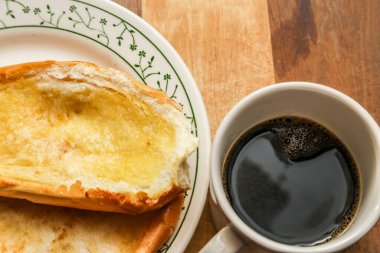 Tabakta iki çörek ve tahta bir yüzeyde bir fincan kahve..