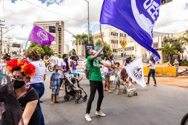 Protesto etmek için kocaman mor bir bayrak sallayan bir çocuk. Fotoğraf Goiania 'da bir kadın günü protestosu sırasında çekildi..