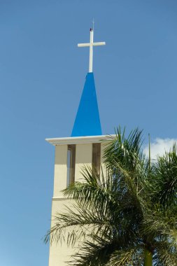  Nossa Sinyora Aparecida Kilisesi 'nin tepesinde. Arka planda beyaz bir haç ve mavi gökyüzü var. Goiania şehrinde..