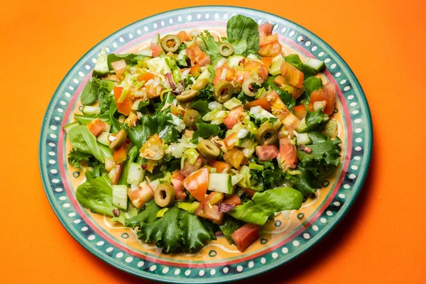 野菜サラダのプレート オレンジの表面に皿の中の野菜の混合物 — ストック写真