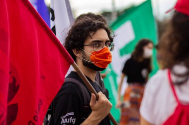 Elinde bayrak tutan genç bir adam. Fotoğraf, Goiania şehrinde Başkan Bolsonaro 'ya karşı düzenlenen bir protesto sırasında çekildi..