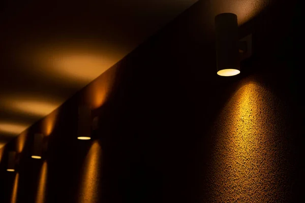 Несколько Подсвеченных Мест Несколько Прожекторов Освещающих Желтую Текстурированную Бетонную Стену — стоковое фото