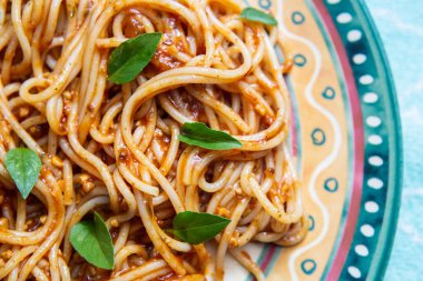 Makarnalı bir tabağın ayrıntıları. Domates soslu makarna ve fesleğen yaprağı..