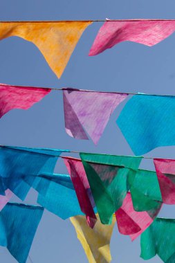 Arka planda mavi gökyüzü olan çamaşır ipinde birçok renkli flamalar asılı. Festa Junina. Quadrilha.