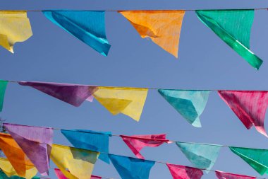 Arka planda mavi gökyüzü olan çamaşır ipinde birçok renkli flamalar asılı. Festa Junina. Quadrilha.