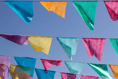 Arka planda mavi gökyüzü olan çamaşır ipinde birçok renkli flamalar asılı. Festa Junina. Quadrilha.