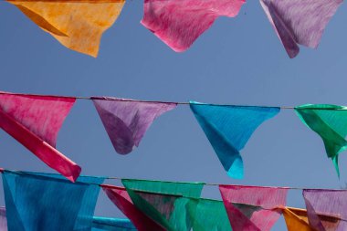 Arka planda mavi gökyüzü olan çamaşır ipinde birçok renkli flamalar asılı. Festa Junina. Quadrilha.