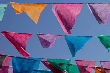 Arka planda mavi gökyüzü olan çamaşır ipinde birçok renkli flamalar asılı. Festa Junina. Quadrilha.