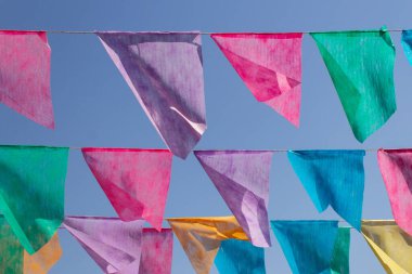 Arka planda mavi gökyüzü olan çamaşır ipinde birçok renkli flamalar asılı. Festa Junina. Quadrilha.