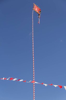 Kutsal Babamızın tacını taşıyan bayrak direğe işlenmiş, etrafında bayraklar olan..