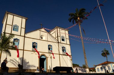 Pirenopolis şehrinde düzenlenen geleneksel bir dini festival olan Cavalhadas için dekore edilen Igreja Matriz Nossa do Rosario 'nun önündeki bazı turistler.