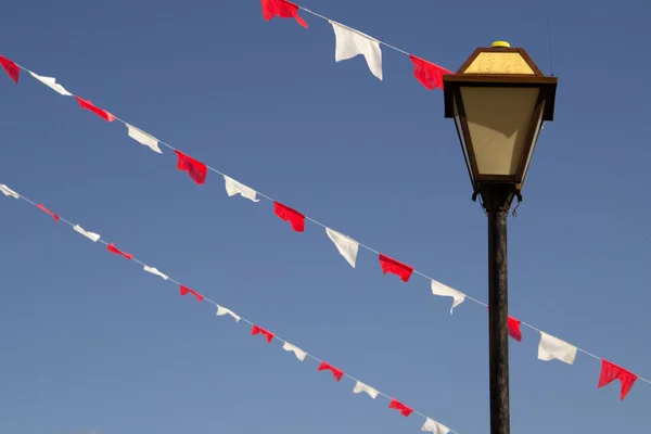 背景に青い空を背景に白と赤の旗のラインとストリートランプのヴィンテージ ランプポスト 旗ランプ — ストック写真