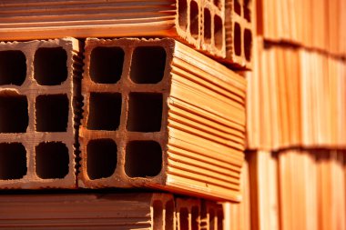 Ceramic bricks arranged in piles and stored outdoors for sale. A Detail of stacked bricks.
