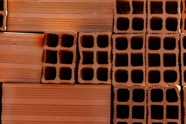Ceramic bricks arranged in piles and stored outdoors for sale. A Detail of stacked bricks.