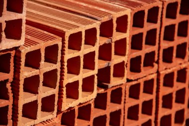 Ceramic bricks arranged in piles and stored outdoors for sale. A Detail of stacked bricks.