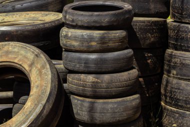 Özel bir dükkanda yığılmış bir sürü farklı boyutta eski ve kirli lastik. Lastik lastikler kullanılmış..