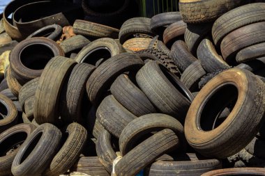 Özel bir dükkanda yığılmış bir sürü farklı boyutta eski ve kirli lastik. Lastik lastikler kullanılmış..