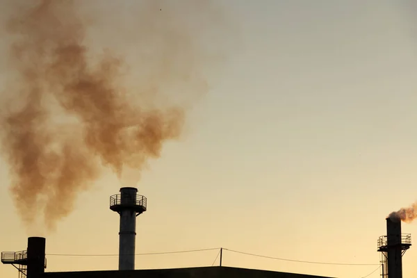 Smoke coming out of the factory chimney. Air pollution by smoke coming out of the three factory chimneys.