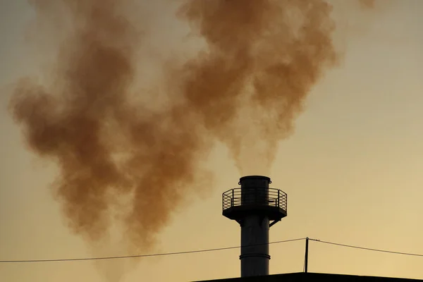 Smoke coming out of the factory chimney. Air pollution by smoke coming out of a factory chimney with the opaque sky in the background.