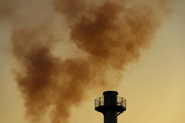 Smoke coming out of the factory chimney. Air pollution by smoke coming out of a factory chimney with the opaque sky in the background.