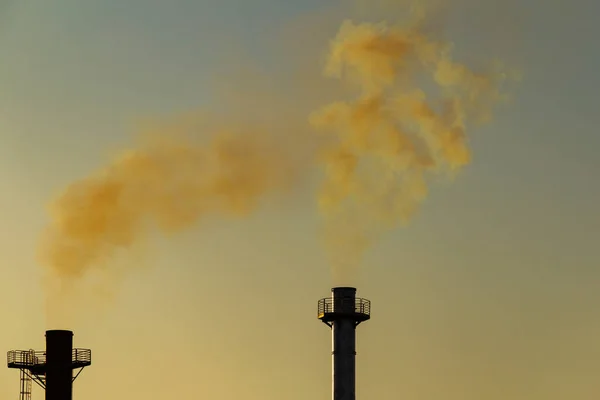 Smoke coming out of the factory chimney. Air pollution by smoke coming out of the two factory chimneys.