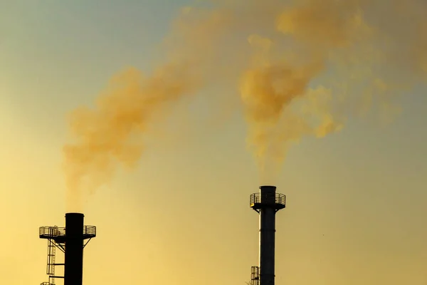 Smoke coming out of the factory chimney. Air pollution by smoke coming out of the two factory chimneys.