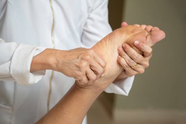 Closeup of massage therapist hands applying therapeutic massage to a patient's foot.