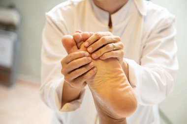  Closeup of massage therapist hands applying therapeutic massage to a patient's foot.
