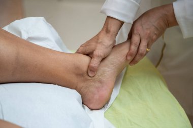  Closeup of massage therapist hands applying therapeutic massage to a patient's foot.