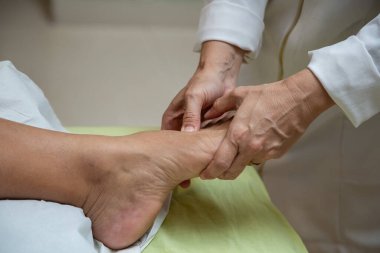 Closeup of massage therapist hands applying therapeutic massage to a patient's foot.