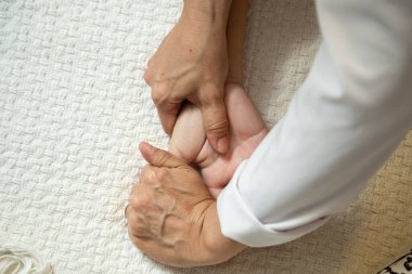 Closeup of masseuse hands applying therapeutic massage on a patient's hand.
