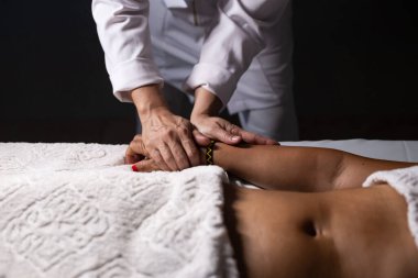 Detail of hands of masseur, who is applying therapeutic massage on the hand of a patient who is lying down.