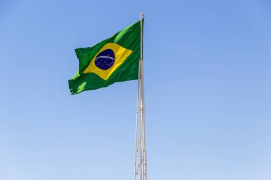 Brezilya bayrağı. Brezilya bayrağı dalgalanıyor, rüzgarda dalgalanıyor ve arka planda mavi gökyüzü.
