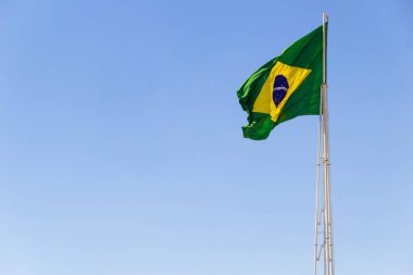 Brezilya bayrağı. Brezilya bayrağı dalgalanıyor, rüzgarda dalgalanıyor ve arka planda mavi gökyüzü.