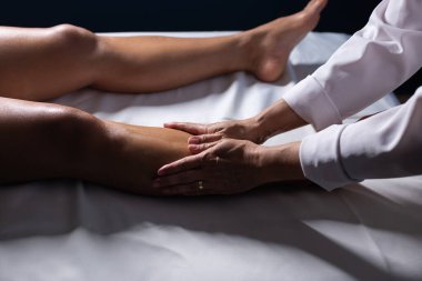 Therapist doing massage to patient. Therapist doing massage on patient's leg.