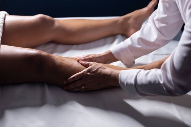 Therapist doing massage to patient. Therapist doing massage on patient's leg.