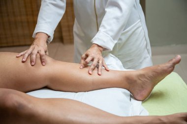 Therapist doing massage to patient. Therapist doing massage on patient's leg.