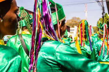 Yeşil elbiseli, dans eden ve perküsyon enstrümanları çalan katılımcılar, tipik bir Brezilya dini festivali olan Congadas 'ta.