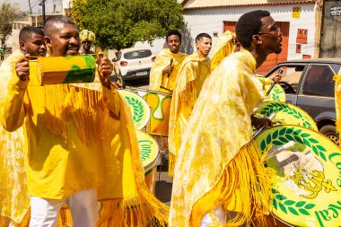 Bazı şenlikler sarı giyinmiş, perküsyon enstrümanları çalıyor, şarkı söylüyor ve dans ediyor, Goinia 'daki Kongadas sırasında, bir Afro-Brezilya kültürel ve dini dışavurumu.