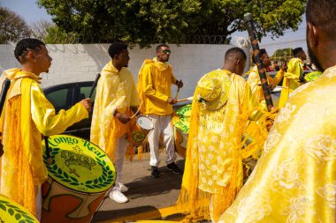 Bazı şenlikler sarı giyinmiş, perküsyon enstrümanları çalıyor, şarkı söylüyor ve dans ediyor, Goinia 'daki Kongadas sırasında, bir Afro-Brezilya kültürel ve dini dışavurumu.