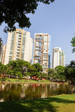Açık bir günde Flamboyant Park 'ın açısıyla gölü ve arka planda bazı binaları görüyoruz..