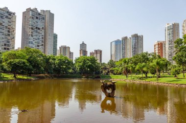 Flamboyant Park 'ın bir açısı, arka planda gölü, ağaçları ve binaları gösteriyor..