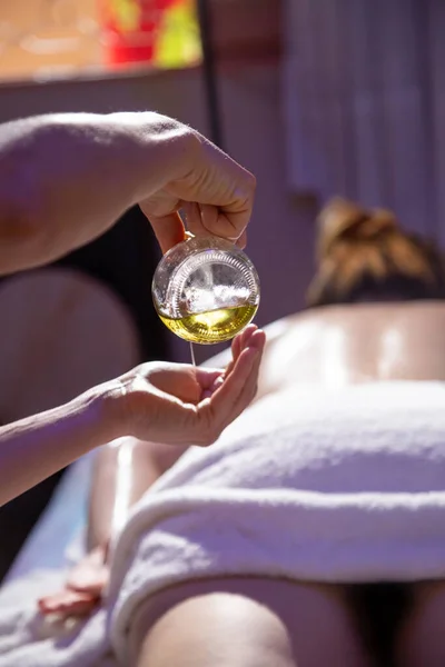 Massagem Terapeuta Derramando Óleo Sobre Mãos Com Paciente Deitado Uma — Fotografia de Stock