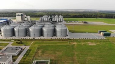 Tahıl asansörü. Tarım bölgesinde metal tahıl asansörü. Hasat için tarım deposu. Yeşil doğa arka planında tahıl asansörleri. Tarım fabrikasının dışı..