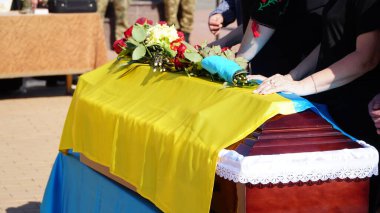 Cenaze vazosunda küller ve cenazede çiçekler. Çiçeklerle süslenmiş bir vazo ve cenaze töreninde yas tutan insanlar. Üzücü ve kederli bir şekilde ölen kişiye veda ediyorlar. n